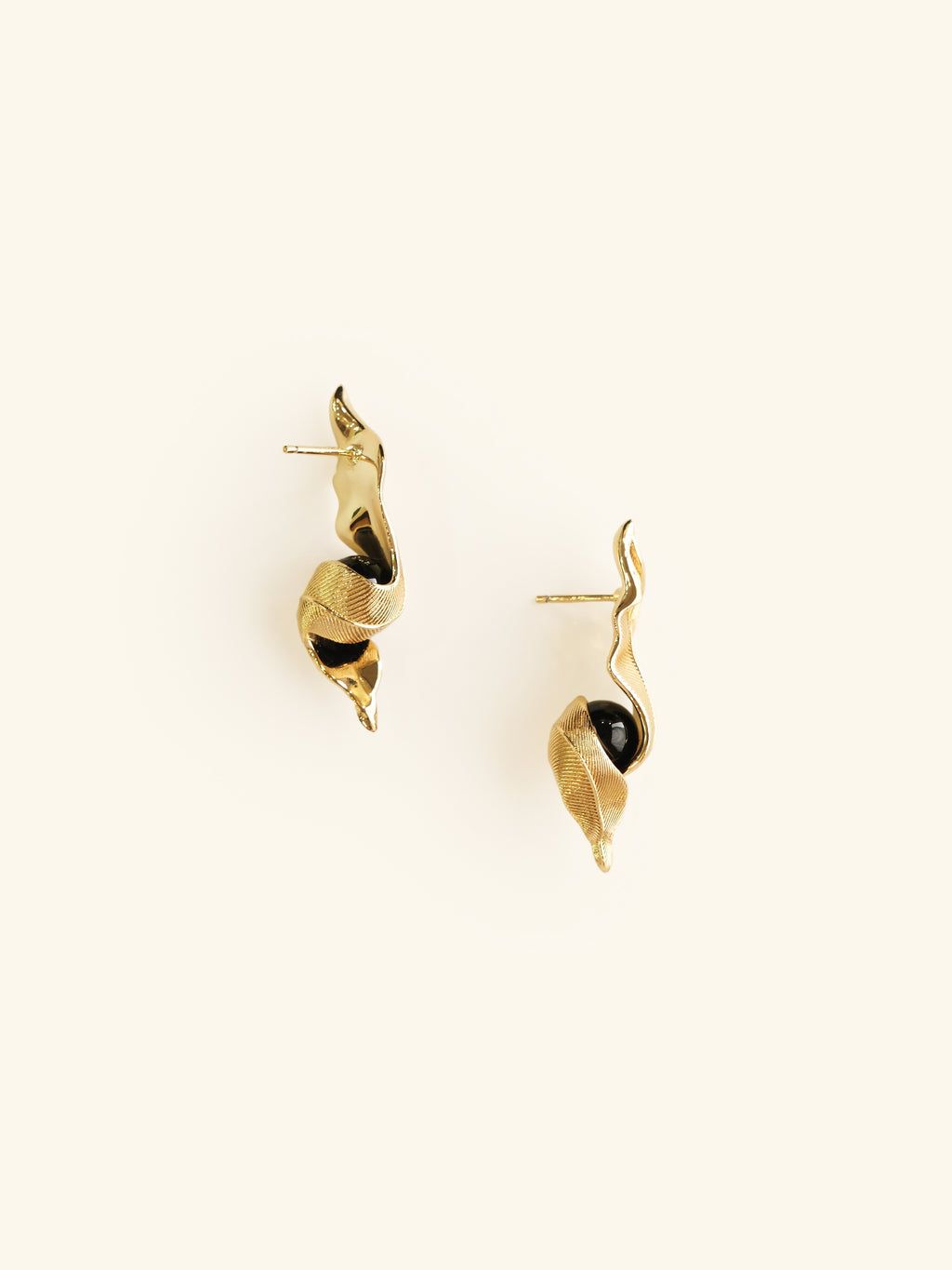Gold leaf-shaped earrings on a white background