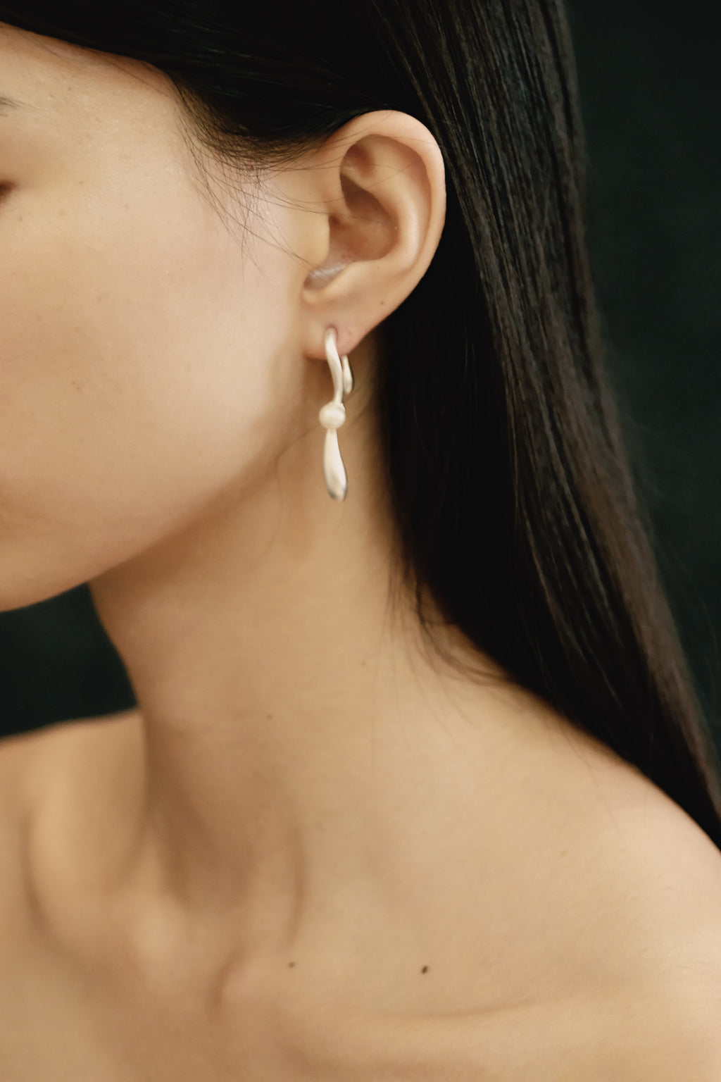 Close-up of a person wearing a delicate earring with a dark background
